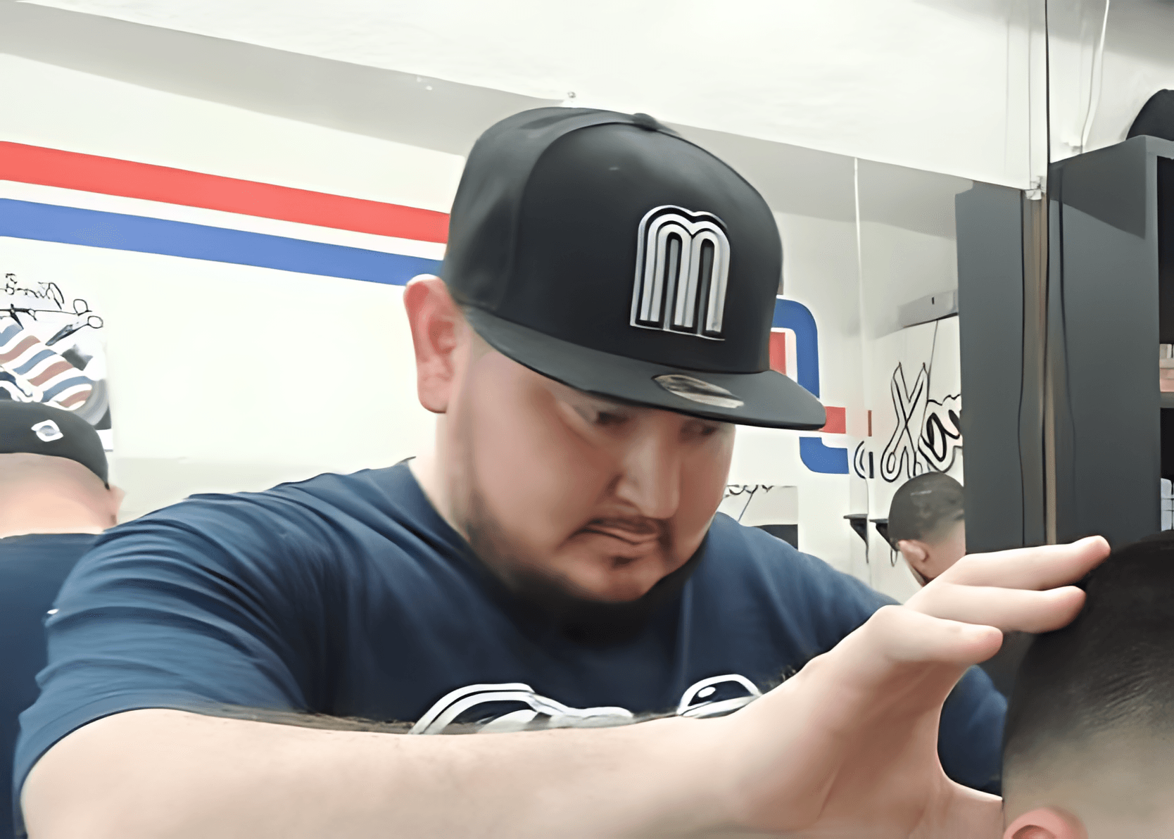 Barbero cortando cabello en El Guero Barbershop